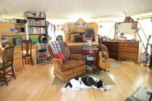 Happy dog, guitar and book shelves paint a cozy picture of the interior of this living tent home, a Yome by Red Sky Shelters
