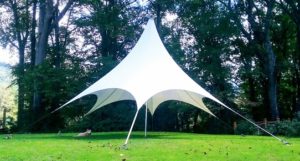 Pinnacle branded large white event tent in the sun by the forest edge