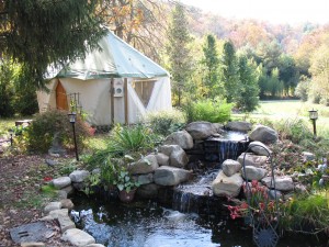 Yurt home aka Yome by Red Sky Shelters shown by beautiful water feature pond with waterfall and stones