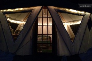 Beautifully illuminated Yome branded yurt home seen from outside at night through expansive windows
